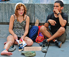 On the corner of Fifth Avenue and 60th Street -- i.e., at the opposite end of the block where the iPhone fans were waiting in line -- this young couple staked out a spot with a sign that said "Feed us." I gave them some money; I hope they did use it to buy some food ... Silly me: after the iPhone 3g had been out for a full week, I thought I could stroll right into the Apple Store on Fifth Avenue & 59th Street in mid-town Manhattan, and simply buy one without any muss, fuss, bother, or delay. But when I arrived at 11 AM, I found a line of approximately 150 people waiting outside in the broiling sun, not seeming to move forward at all; it turned out that the Apple store "concierge" folks were letting them in in groups of ten, when the previous ten had been taken care of. When I asked the woman how long she had been waiting, she said, "Four hours" -- she had arrived at 7 AM, having already determined that the AT&T stores were sold out throughout New Jersey and Connecticut. Well, I'm a gadget freak and a Mac fan, but there's a limit to my passion for such things; four hours was just too much. So instead, I decided to take a bunch of pictures of the people who were in the line. Of course, I have no idea whethere the people queued up in front of Apple stores in other cities (or at other stores here in NYC) are similar to this group ... but I'm inclined to think that they are. And if that's true, then the demographics of this group -- in terms of age, gender, nationality, ethnic groups, etc. -- is particularly intriguing. I saw only one guy dressed in a corporate uniform of suit and tie; Apple may be trying to break into the "enterprise" market, but that's not who was standing in line for all those hours in the sun...
