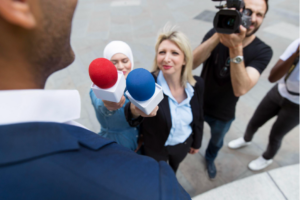 Journalists interviewing a man with blue and red microphone