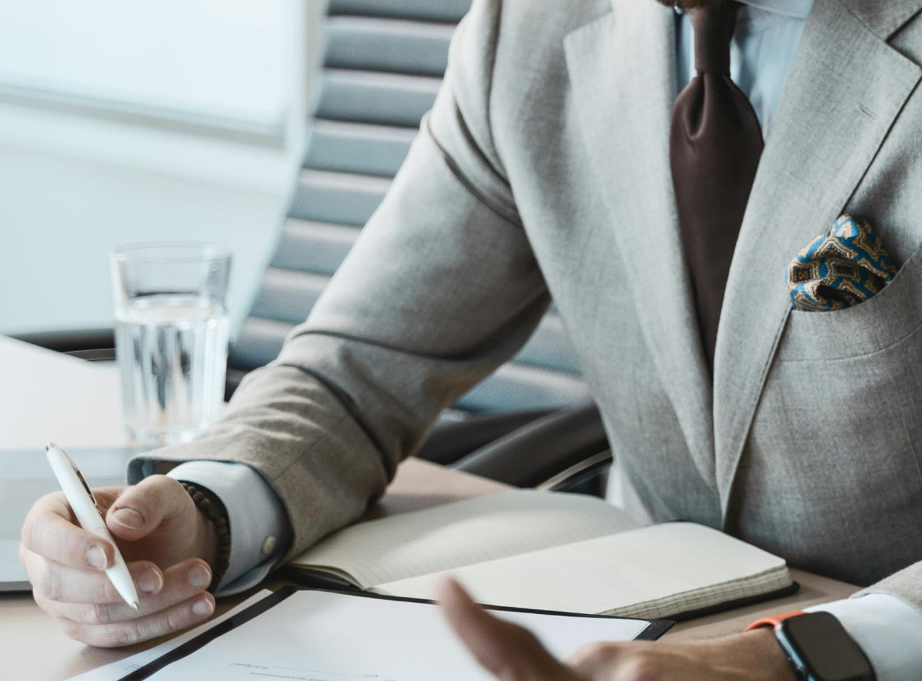 Executive taking notes while reviewing documents at a meeting table
